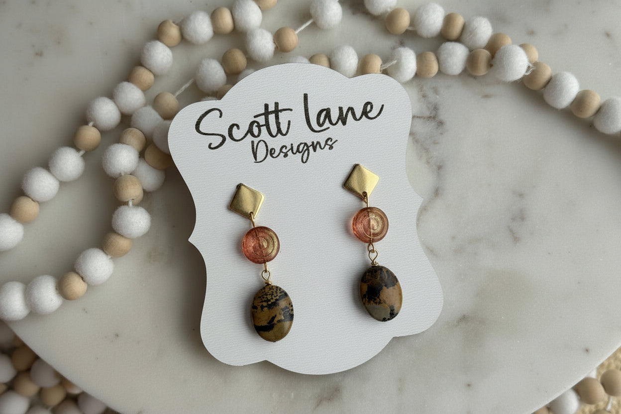 Pair of earrings on a Scott Lane Designs card with beads in the background